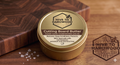 Jar of cutting board butter with 'Hive to Hardwood' branding on a wooden surface.